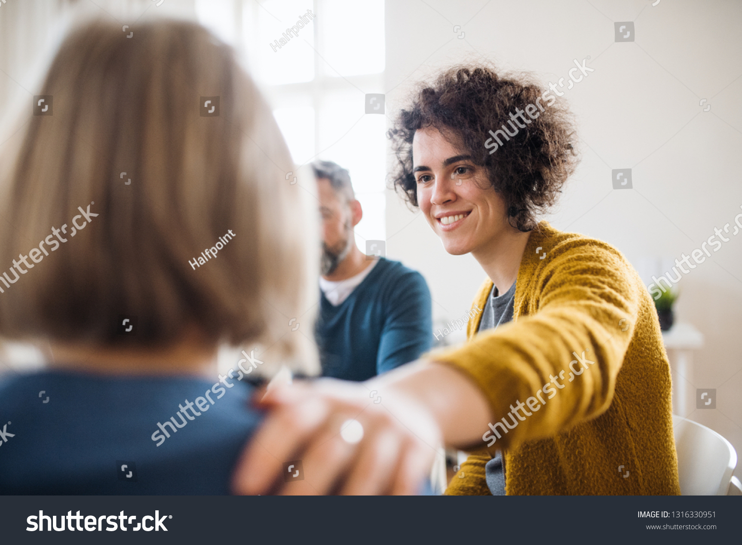 Men and women sitting in a circle during group therapy, supporting each other.