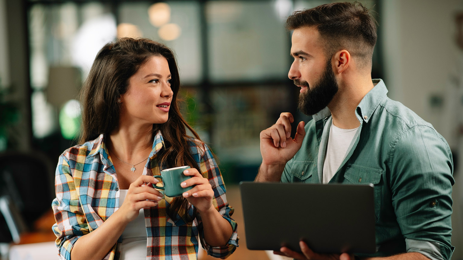 Two coworkers discussing a project in a modern office space