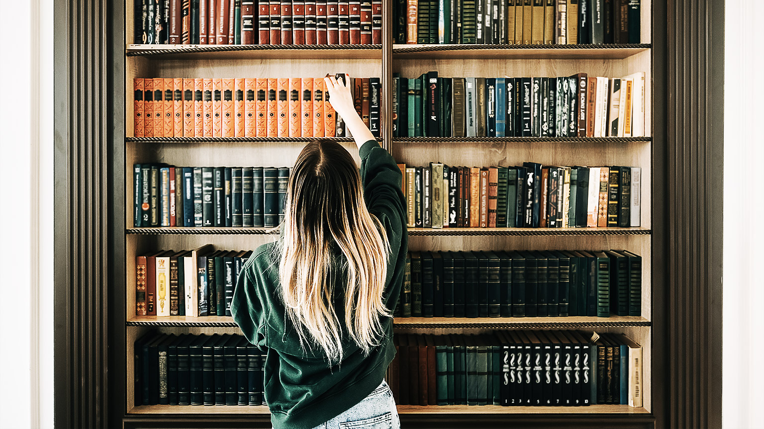 A person reaching for a book in a library