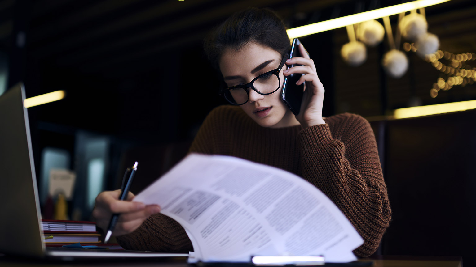 Woman looking at paper while talking on the phone