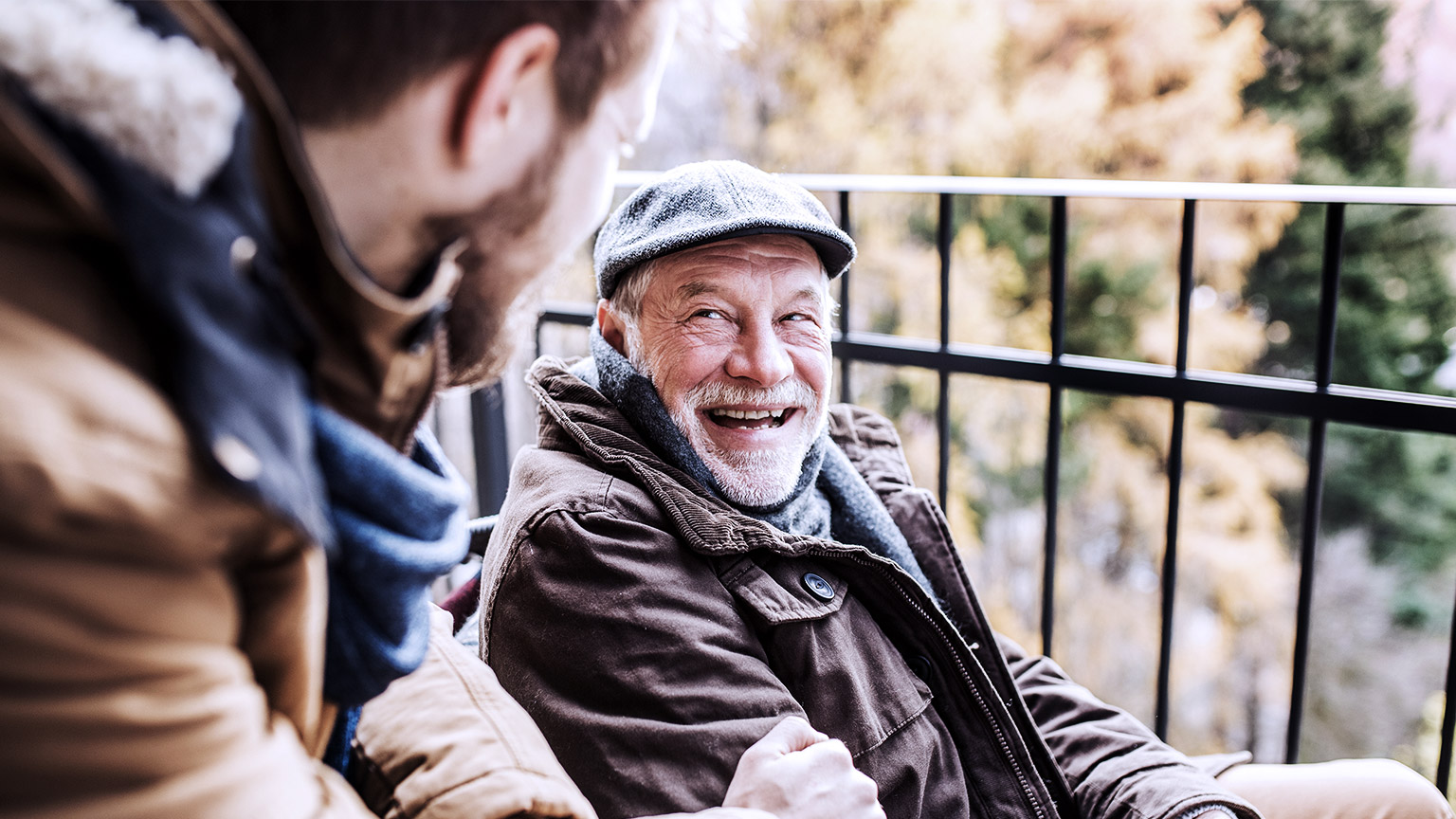 Senior man on wheelchair talking happily with young man