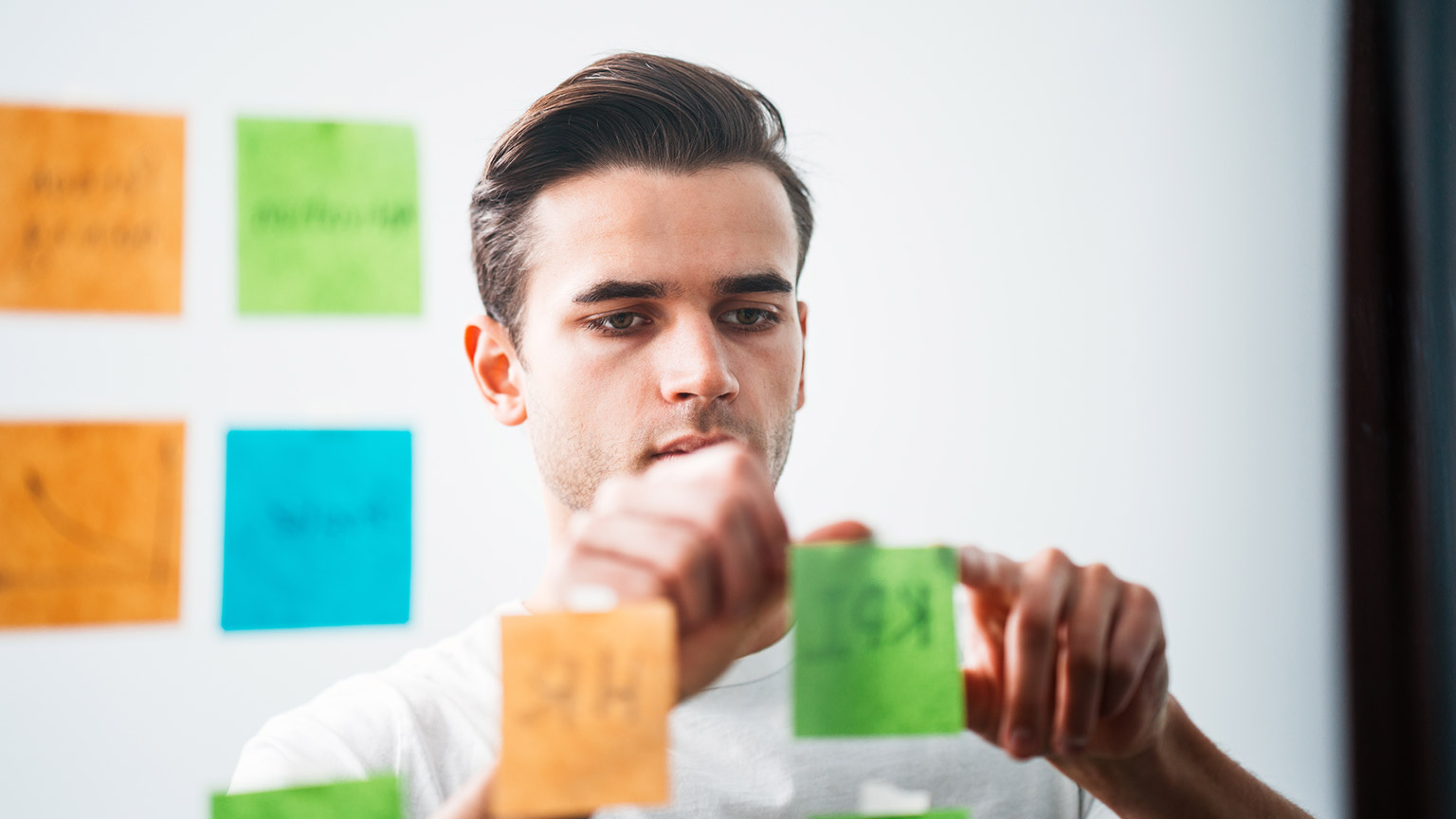 A person writing group roles on sticky notes