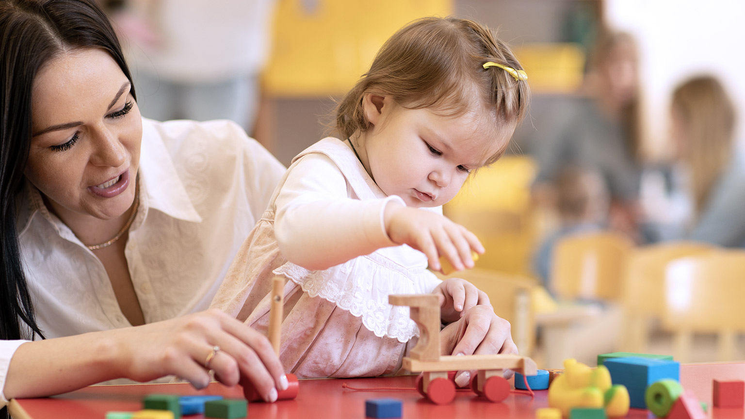 Adult asisting a child in playing wooden toy