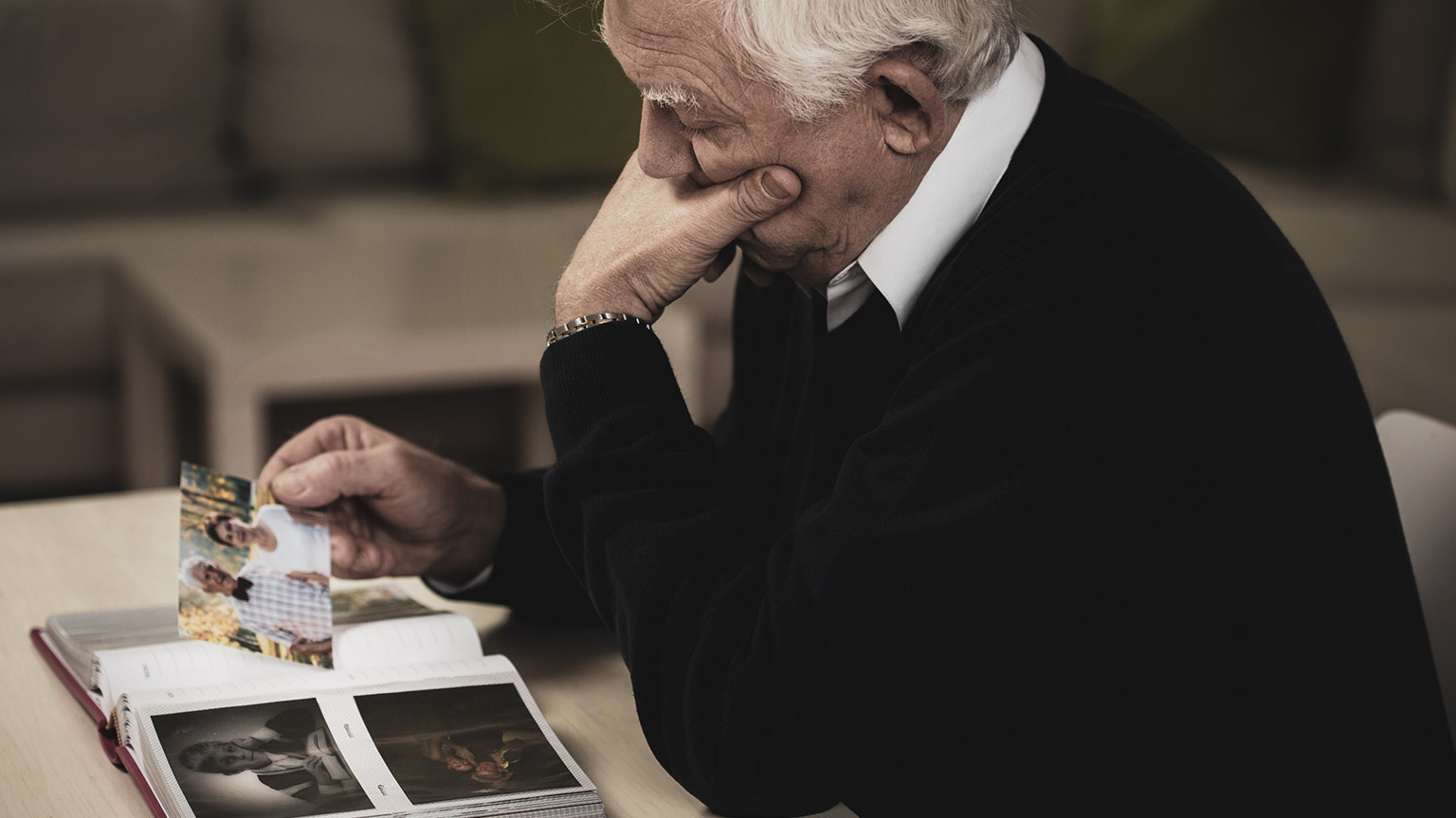 A widower sitting at a table looking at photos