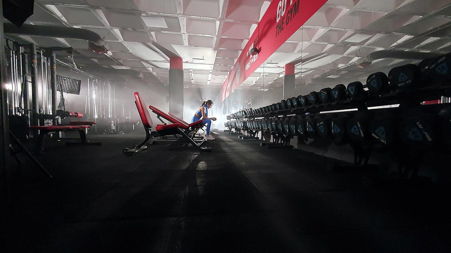 A trainer sitting alone in a spacious gym