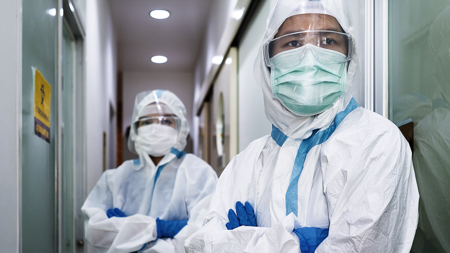 Doctor and nurse in personal protective equipment or ppe including white suit, mask, face shield and gloves