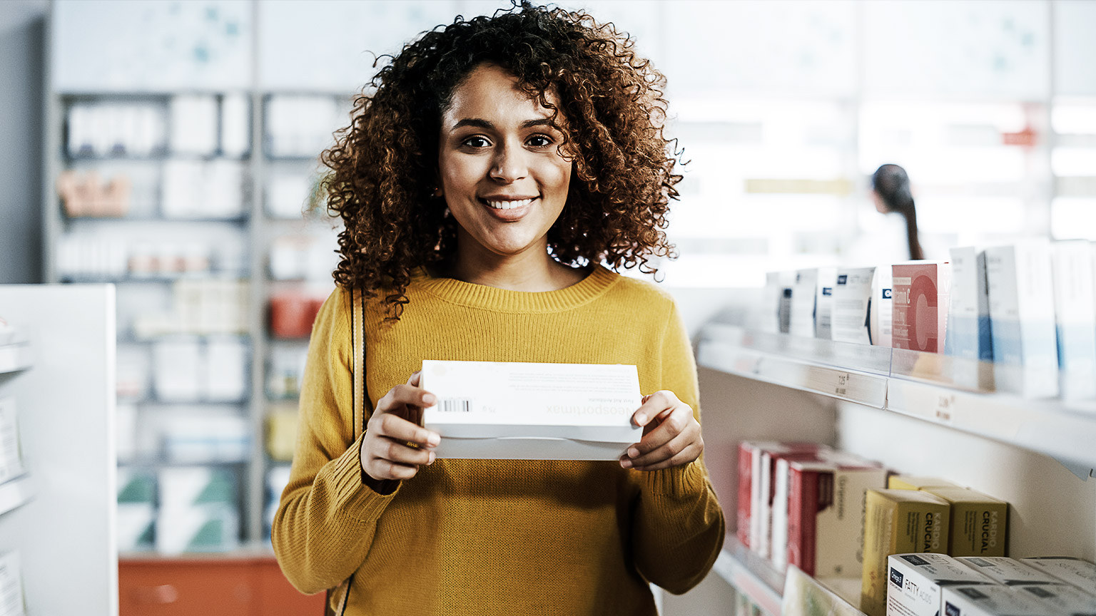 Woman in a pharmacy holding a box of medication