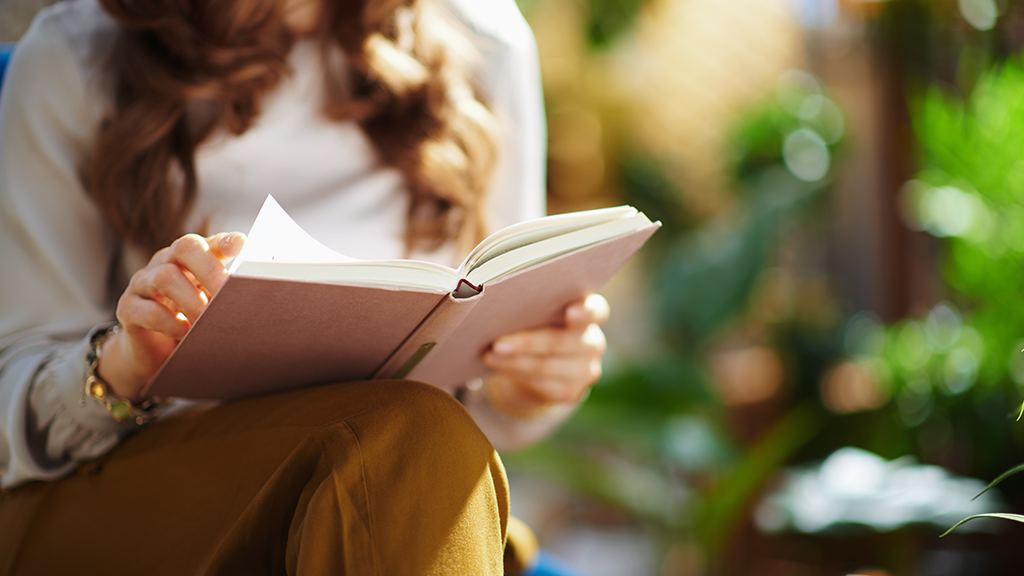 Closeup on female with long wavy hair with book