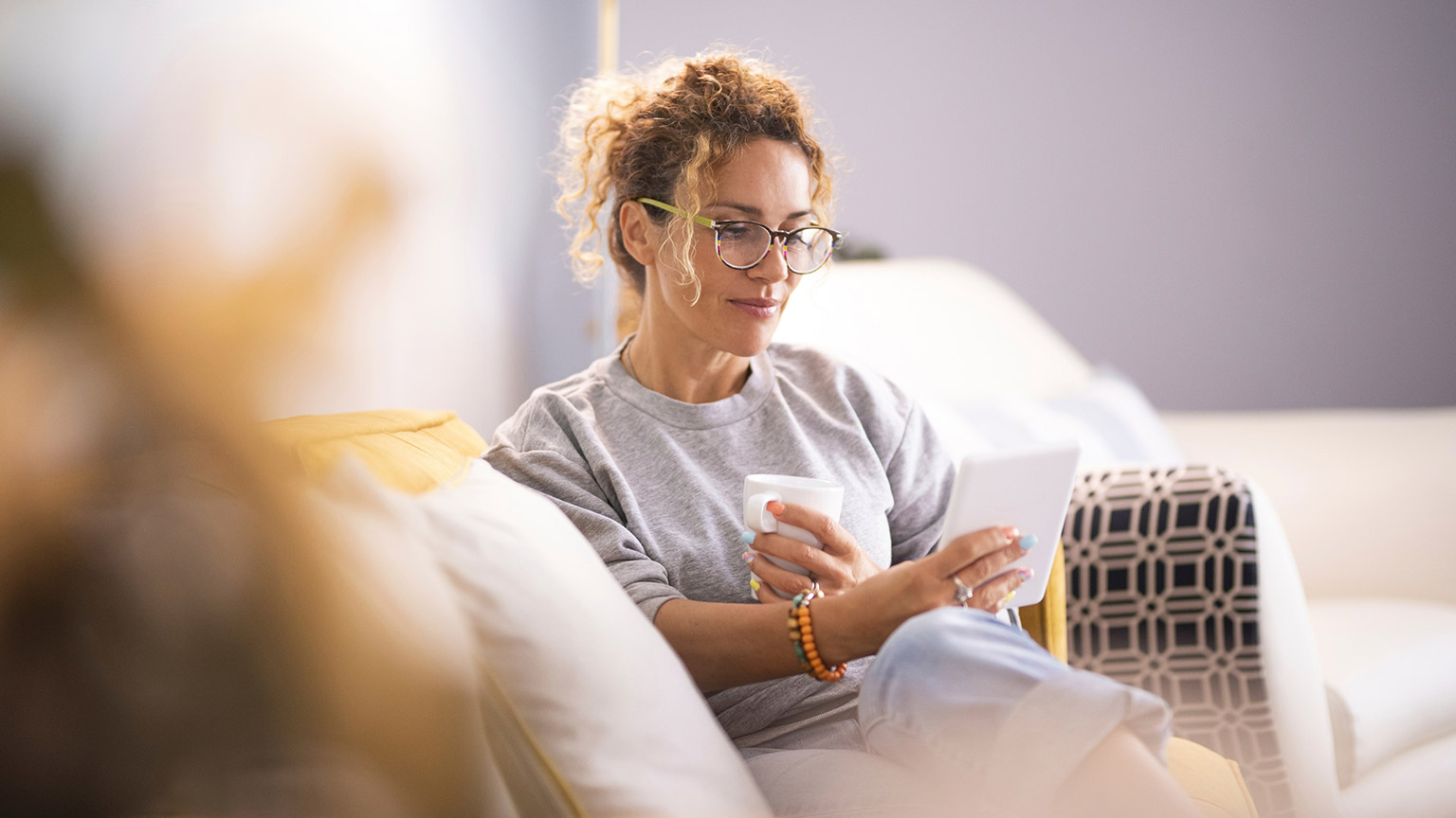 A person sitting on a couch reading information on a tablet device