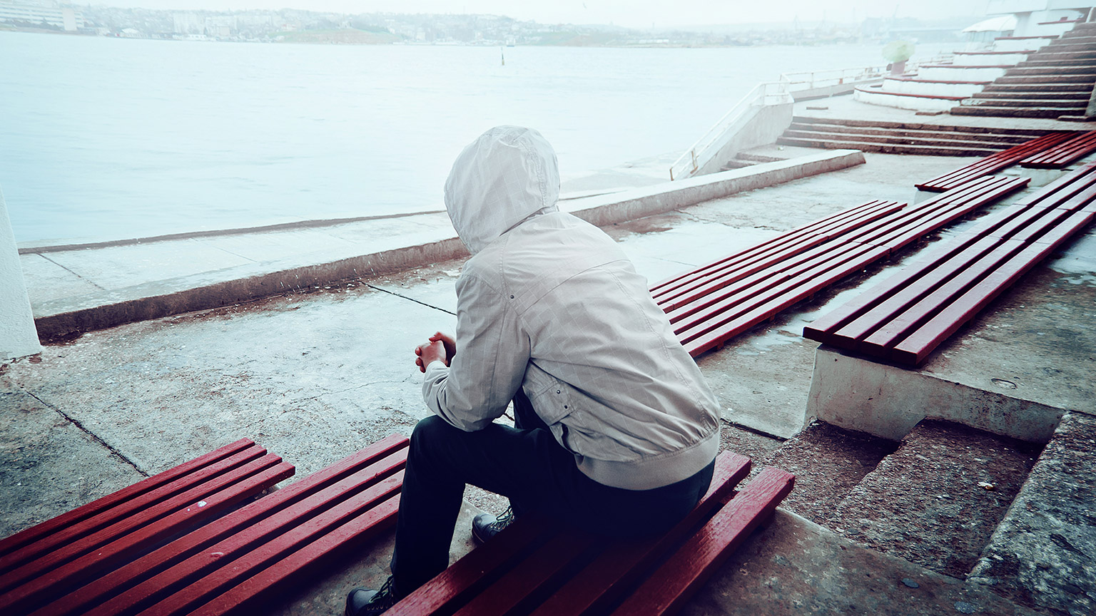 A person sitting alone outside on a bleak day