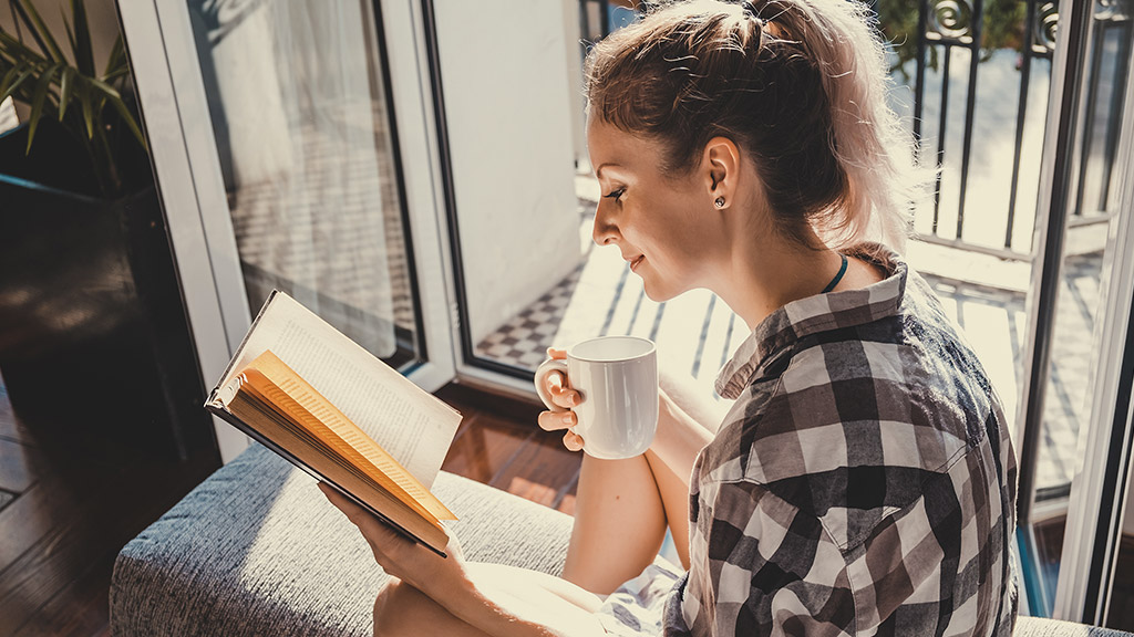 a lady reading a book and holding a cup