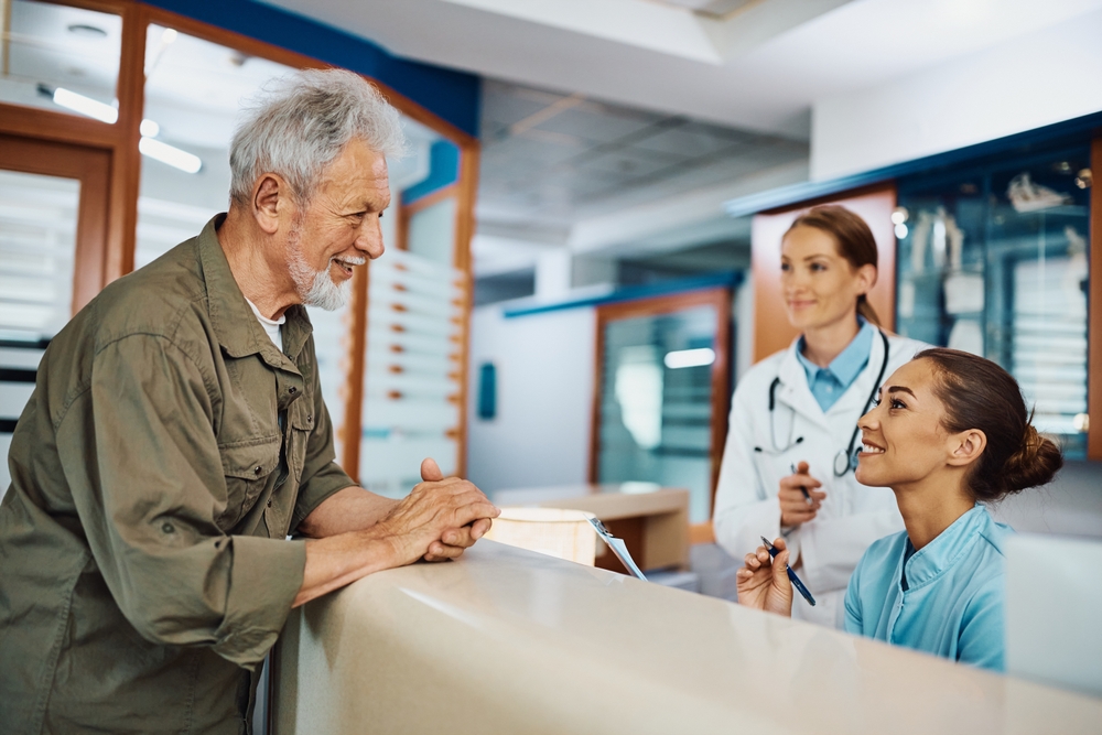 Man at admin desk at a doctors surgery talking to staff