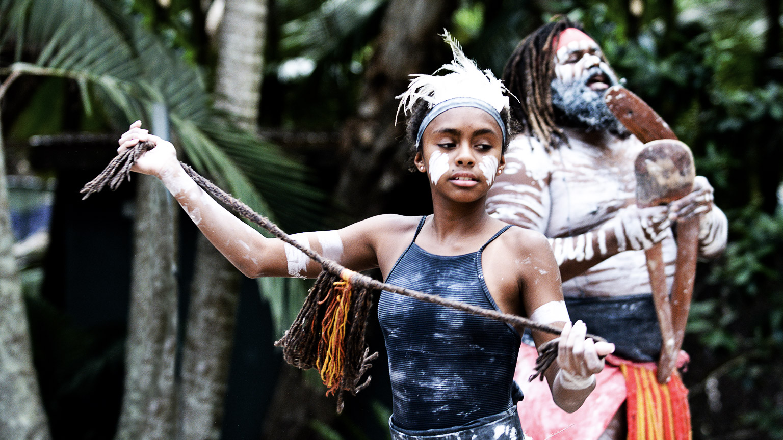 Young adult Australian Aboriginal woman dancing to the singing rhythm sound of Australian Aboriginal adult man in the tropical Queensland, Australia.