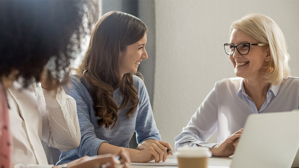 businesswomen talking laughing at corporate group business meeting