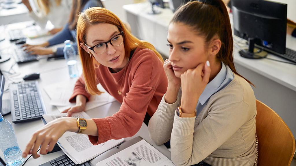 A female student worrying about hard informatics lesson in the university computer classroom