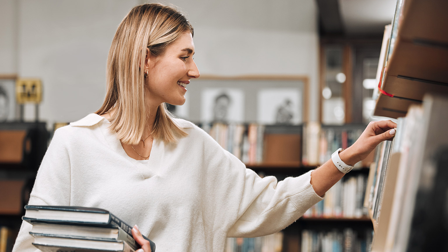 A person in a library choosing a book on a shelf