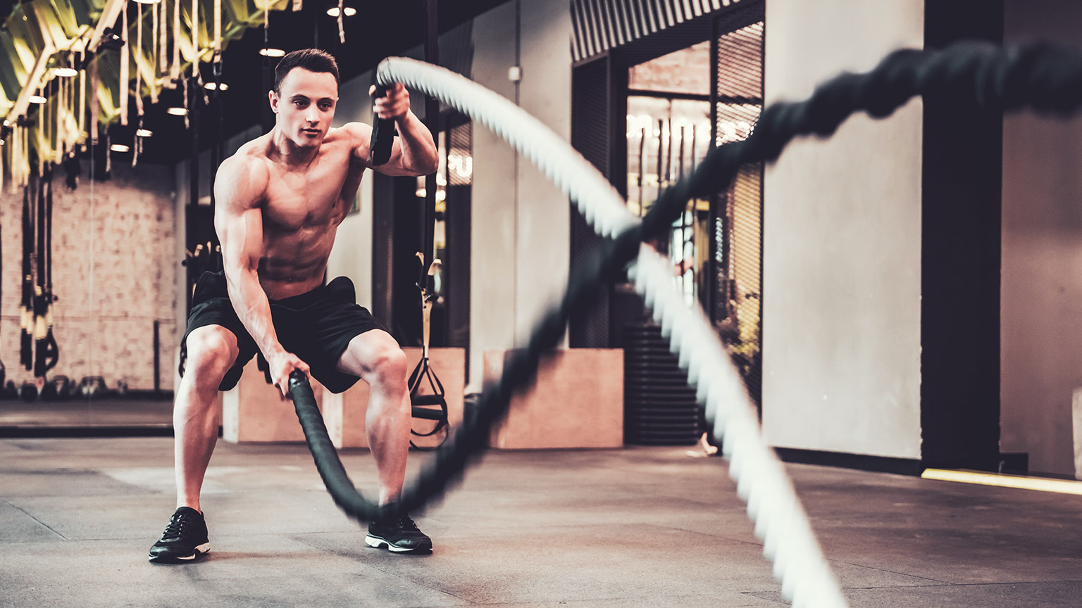 A person in a gym using battle ropes