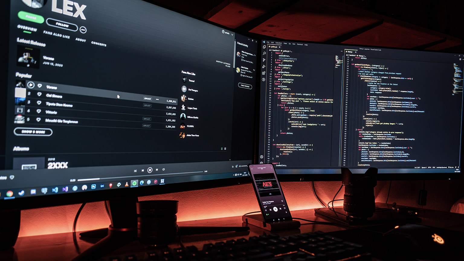 Two screens showing code in a dark room