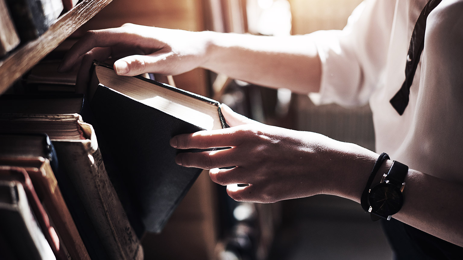 A person getting a book from a rack