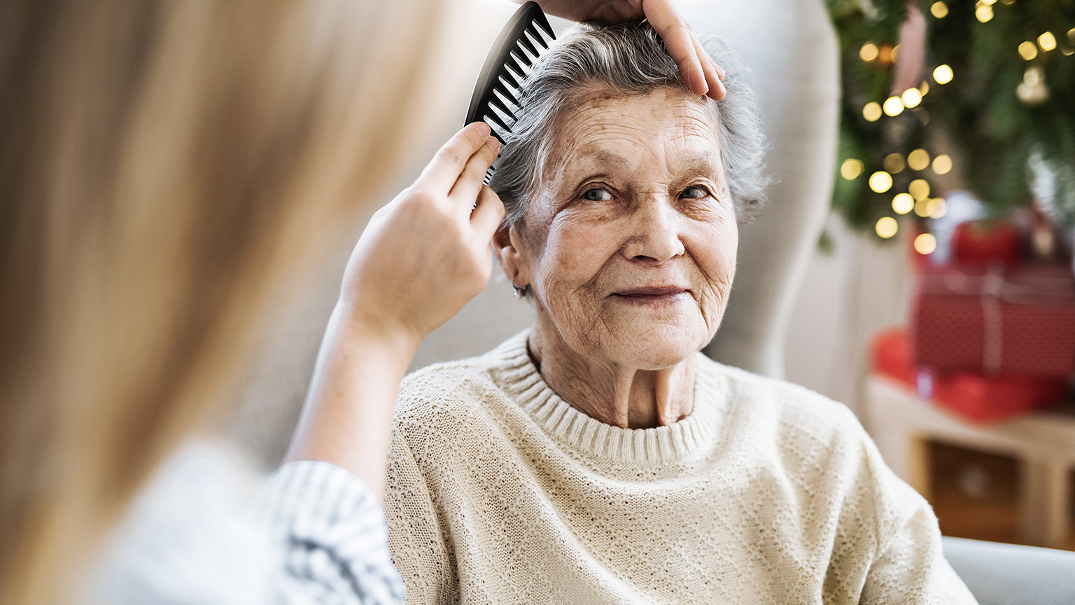 Caretaker combing hair of an elder woman