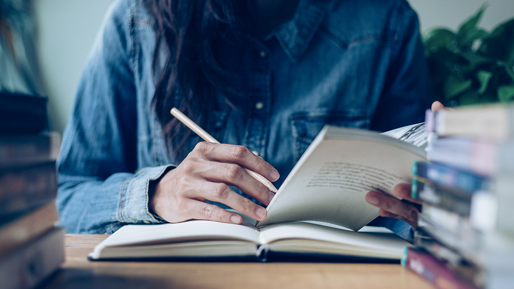 student writing in class room or library at work space