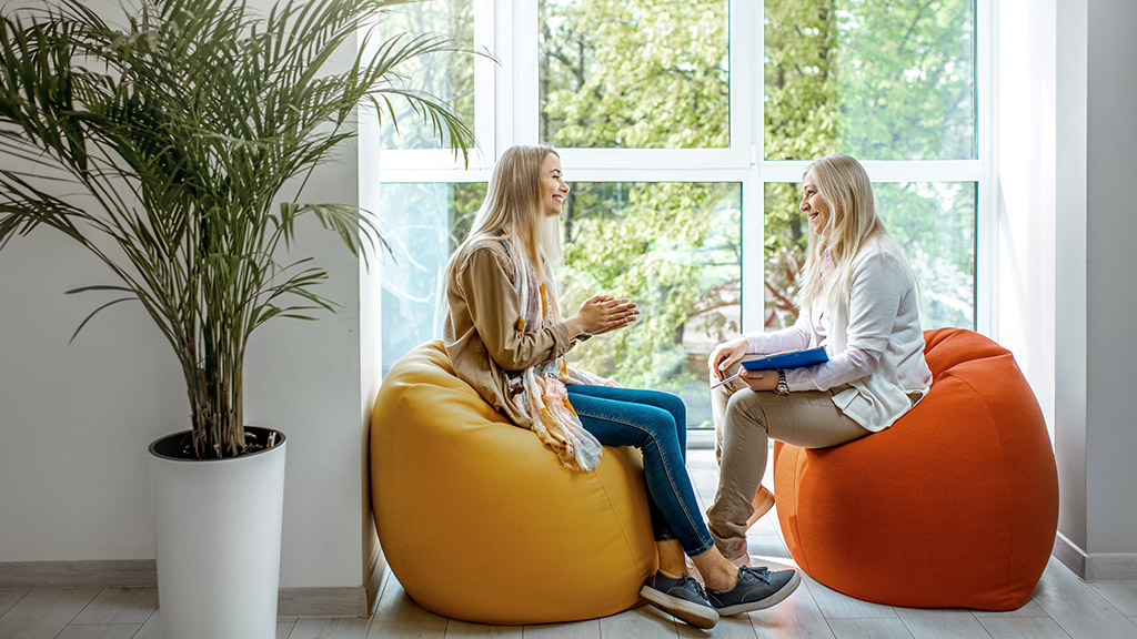 woman with female psychologist sitting on the comfortable chairs during the psychological counseling