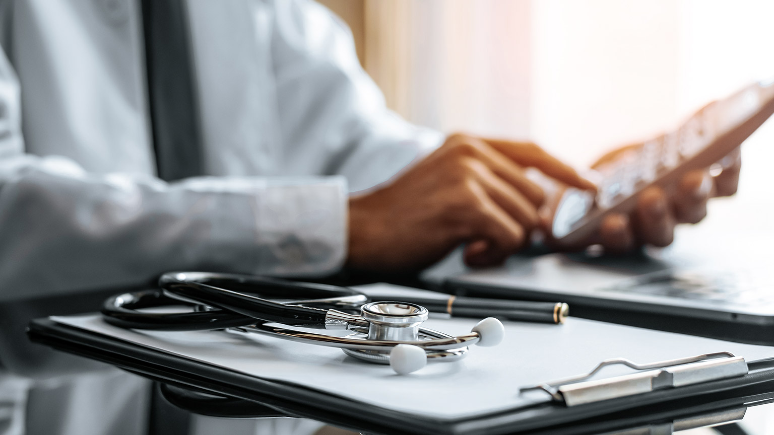 Male doctor using calculator, close-up hands