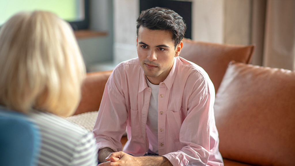 Bad mood. Dark-haired tall man sitting on the sofa and looking upset