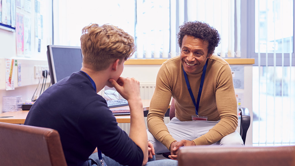 Male College Student Meeting With Campus Counselor Discussing Mental Health Issues