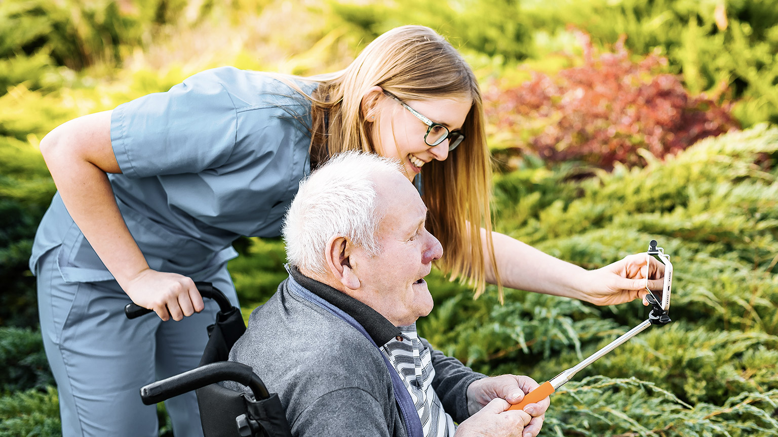 Caretaker assisting an elder for using a phone