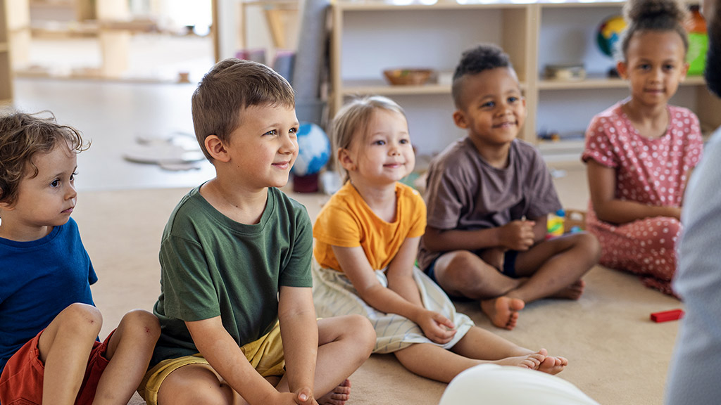 small nursery school children sitting on floor indoors in classroom