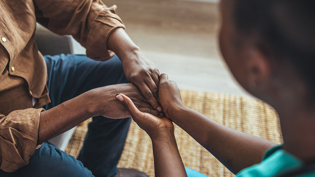 Close-up of home caregiver and senior woman holding hands