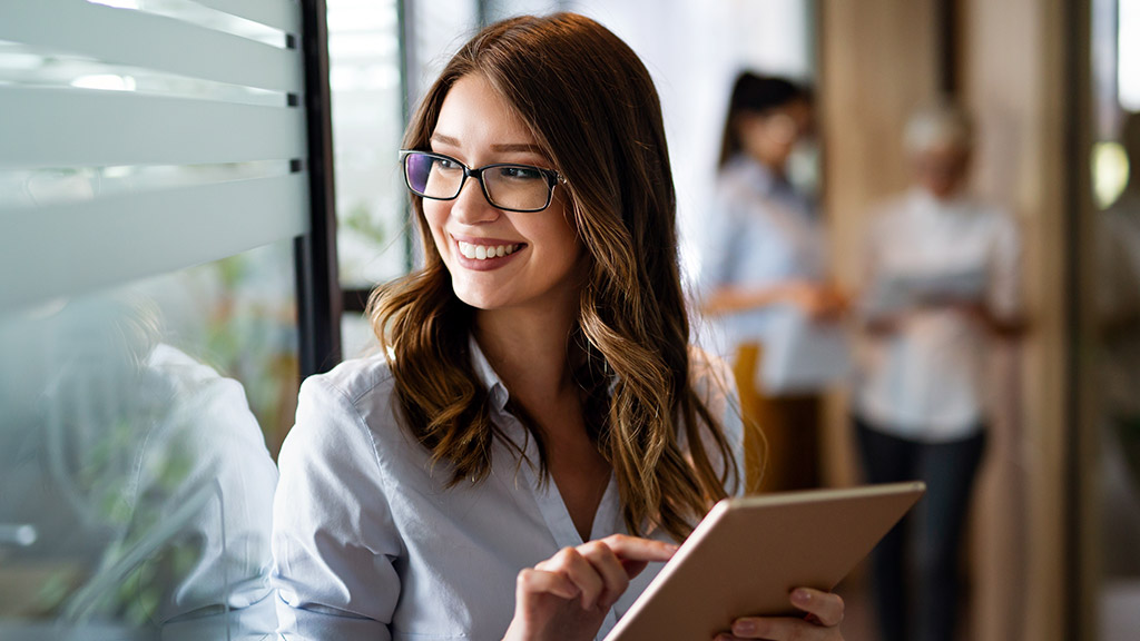 Young happy business woman working with tablet in corporate office