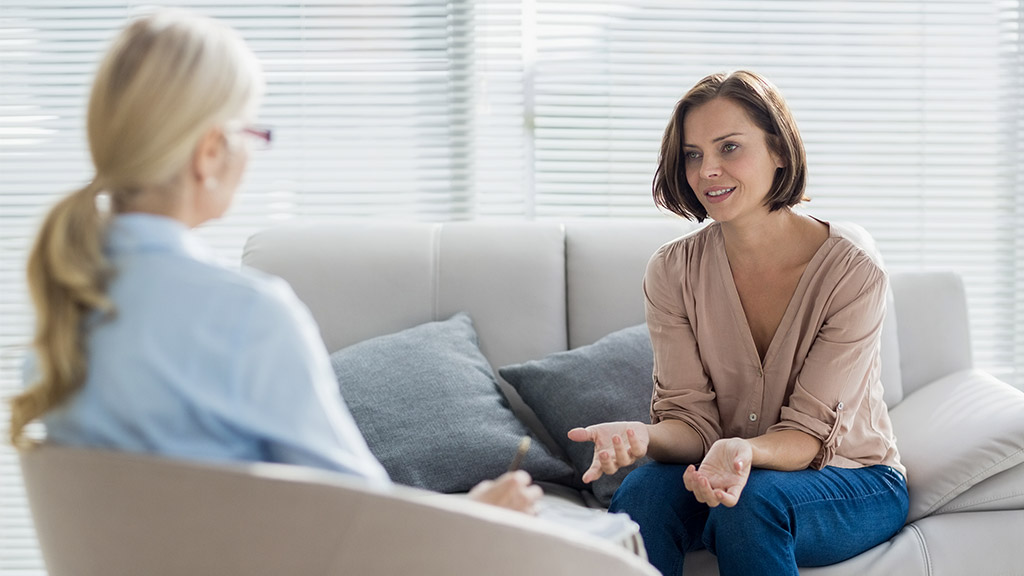 Woman talking to therapist on sofa at home