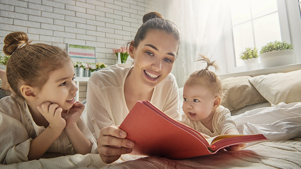 mother reading a book to her daughtersmother reading a book to her daughters