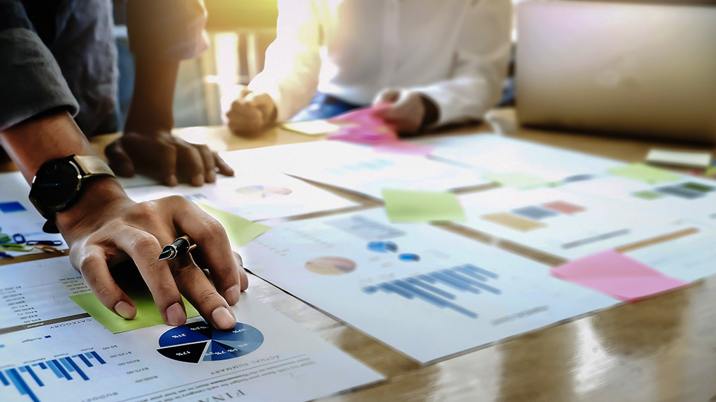 man holding pens and holding graph paper are meeting to plan sales to meet targets