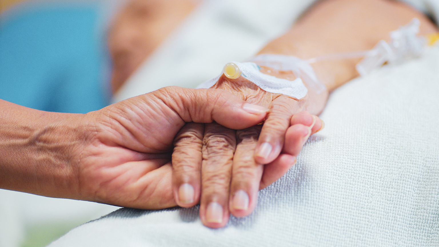 A close view of a person holding the hand of a patient in a hospital