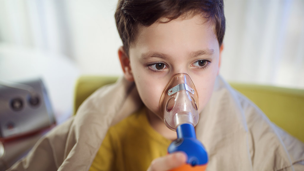 Boy with asthma problems making inhalation with mask on his face