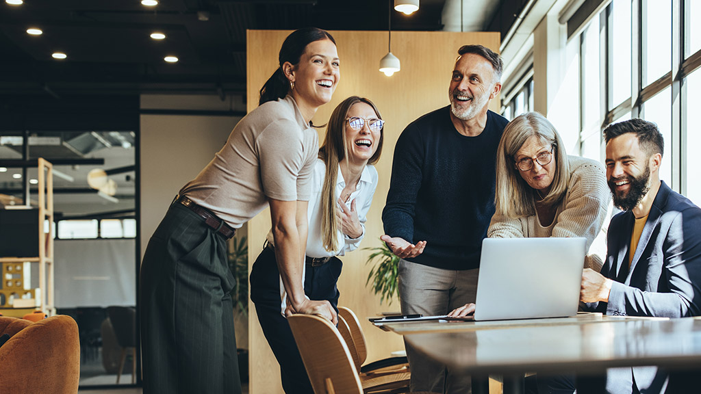 Happy businesspeople laughing while collaborating on a new project in an office