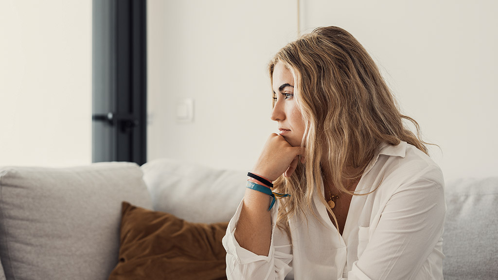 woman looking away at window sitting on couch at home