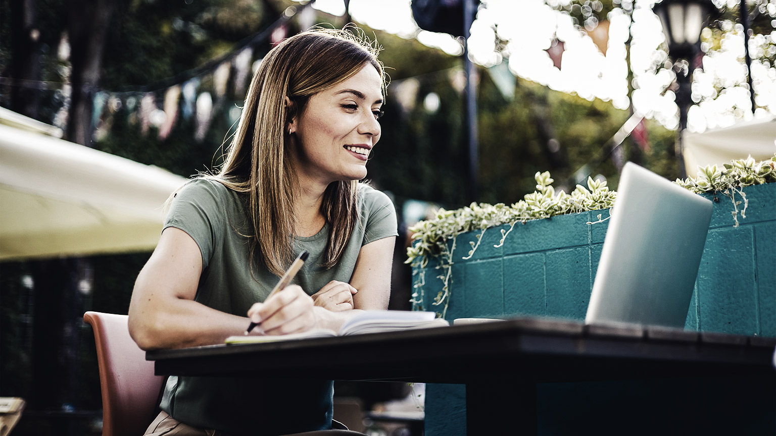 woman sitting on an outdoor lounge reading from a laptop