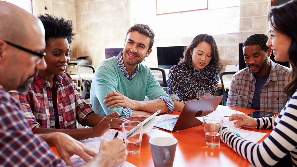 Group Of Designers Having Meeting Around Table In Office