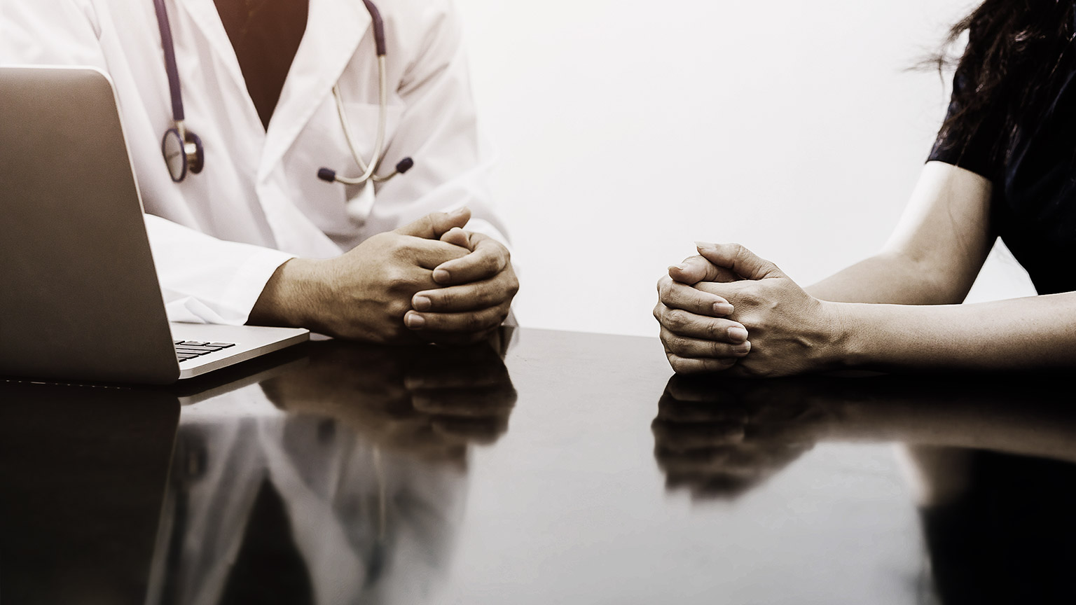 Male doctor and female patient talking on the office desk showing health problem communication between patient and doctor.