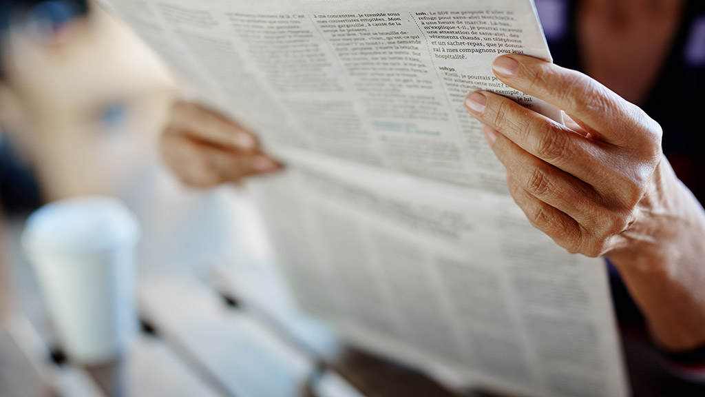 Newspaper broadsheet held and read by senior female