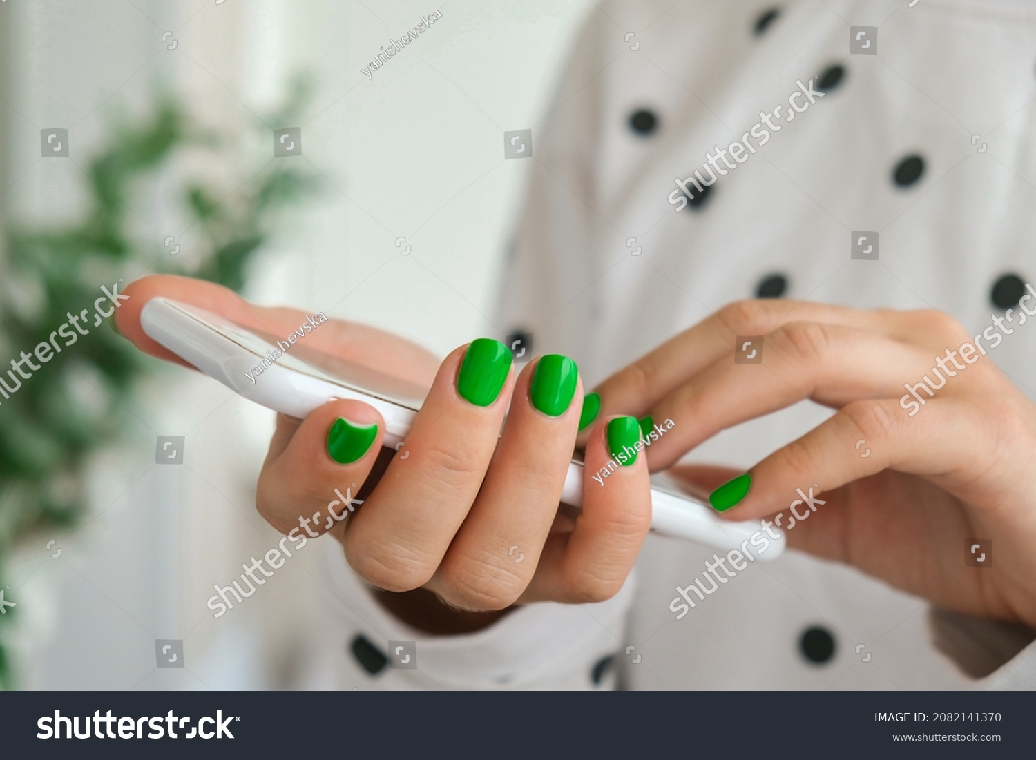 Students hands with stylish green nails holding mobile phone to access online course.