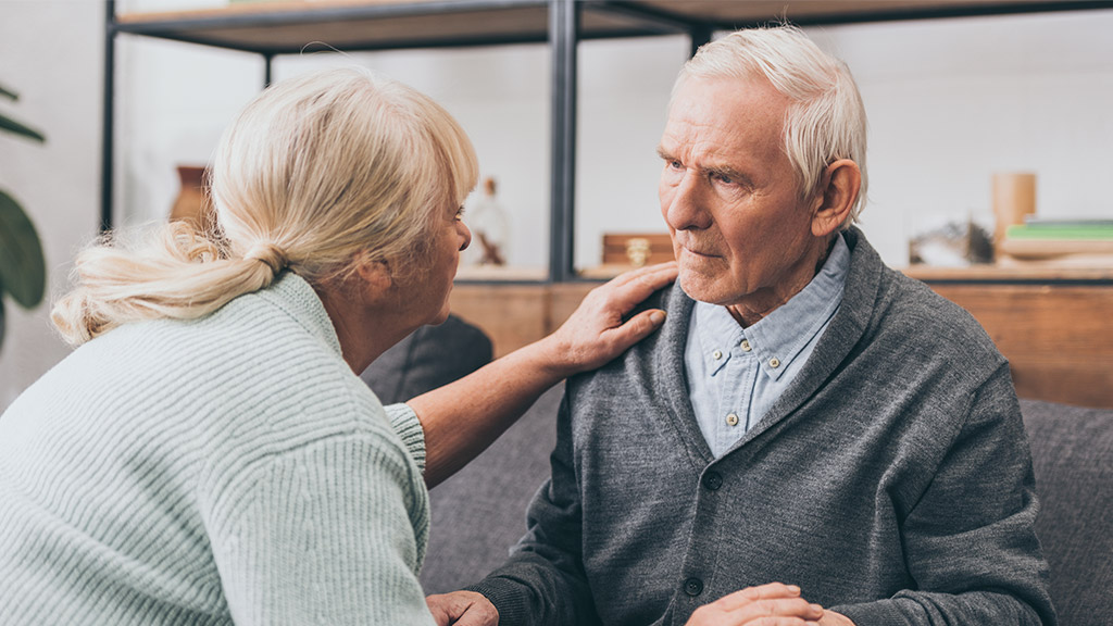 retired couple holding hands and looking at each other at home