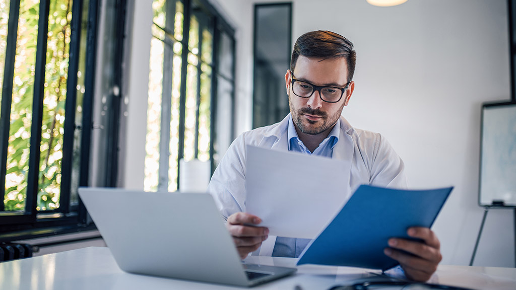 Physician reviewing medical documents at his office