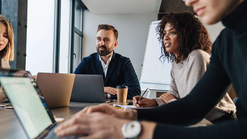 Group of smart multiethnic motivated businesspeople working together on a new project while sitting at the table in the office