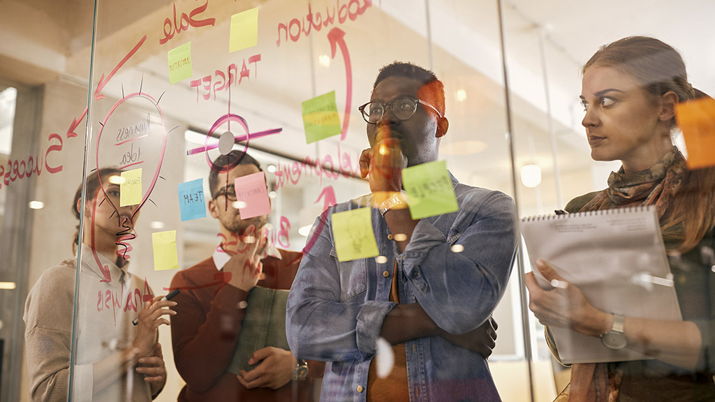 business team thinking of new ideas while making mind map on glass wall in the office