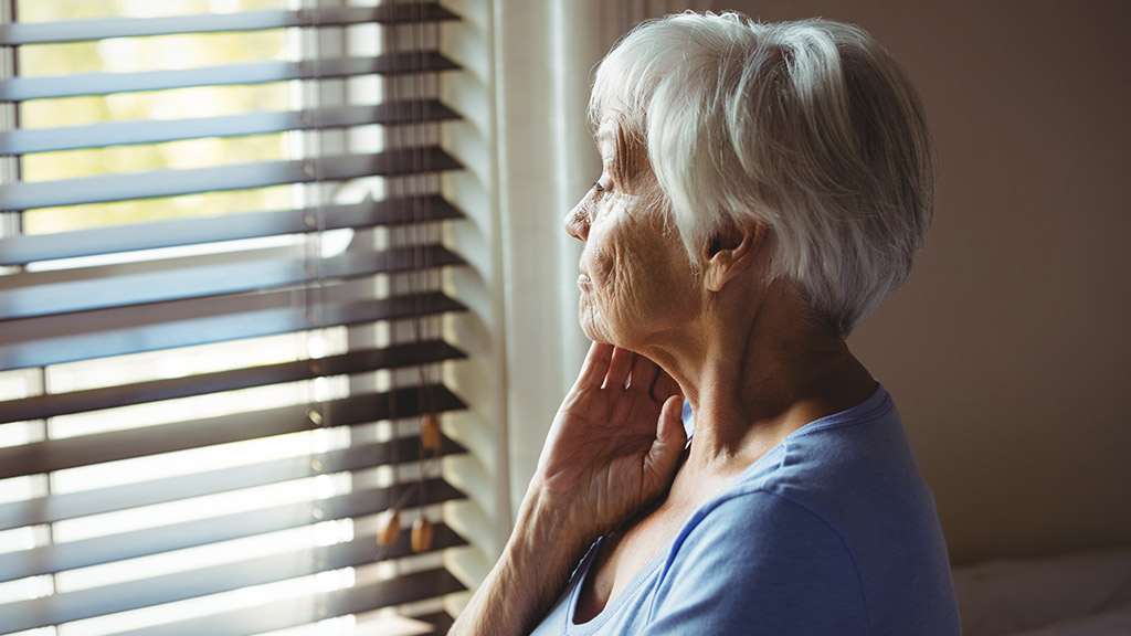 Thoughtful senior woman looking out from window at home